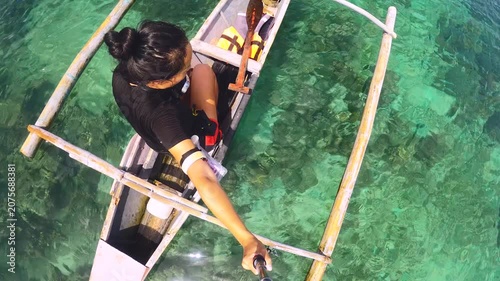 up to bottom side selfie view from a young asian female holding gopro action camera sitting on the small boat looking down to the crystal clear green blue water shallow lagoon through ripple ocean to 