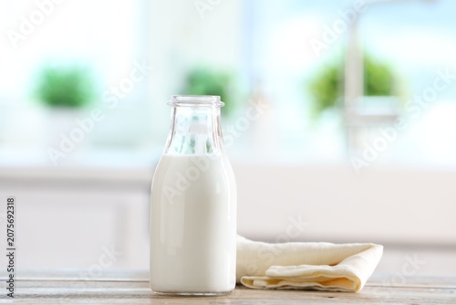 Fotografie Bottle of fresh milk on wooden table in kitchen. Space for text