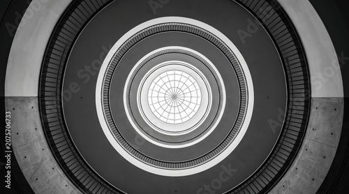 Looking up at the Spiral Staircase in a Building With a Round Ceiling and Large Window During the Day