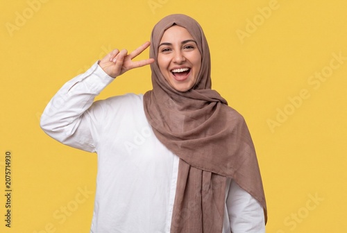 Cheerful young muslim woman showing victory sign