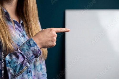 Close up of woman hand pointing at blank white board for advertisement on dark blue background