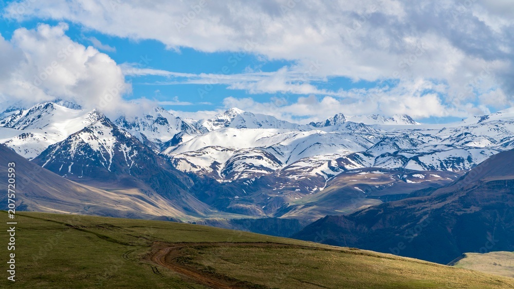Fototapeta premium Dzhily-Su, Russia - June 4, 2026: View of the Caucasus Mountains along the road to Dzhily-Su, showing mountain peaks, valleys, winding road, open landscapes, and scenic natural surroundings.