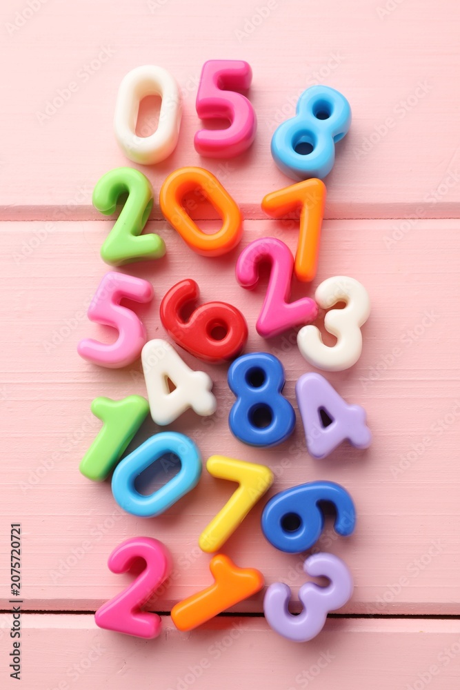 Fototapeta premium Many colorful numbers on pink wooden table, flat lay