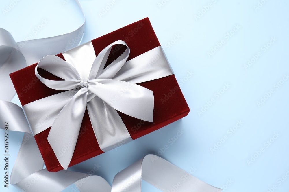 Fototapeta premium Beautiful velvet gift box and ribbon on light blue background, flat lay. Space for text