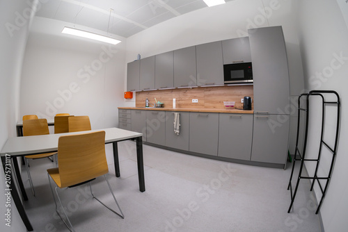 Modern office kitchen area with countertop cabinets tables and seating