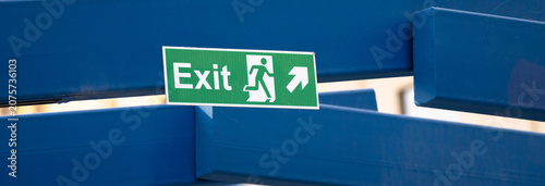 Illuminated emergency exit sign indicating evacuation route in buildings, symbolizing safety guidance, emergency preparedness, and directional information for occupants during hazardous situations.