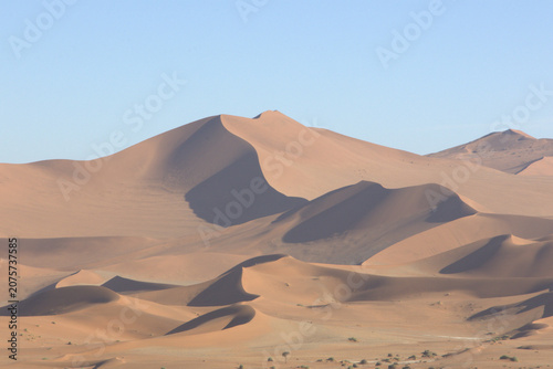 Massive Red Sand Dunes of Sossusvlei Namib Desert Namibia Africa at Sunrise with Dramatic Shadows and Clear Blue Sky