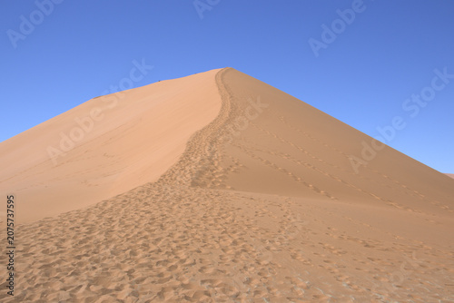 Massive Sand Dune Ridge with Footprints Trail Leading to Peak Against Clear Blue Sky in Namib Desert Sossusvlei Namibia Africa
