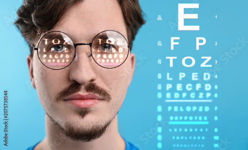 фотографія Man in glasses and eye chart on blue background, selective focus