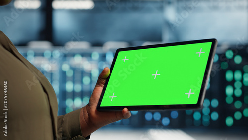 Obraz na plátně Data center technician uses green screen tablet in a data center to inspect hardware and maintain system stability