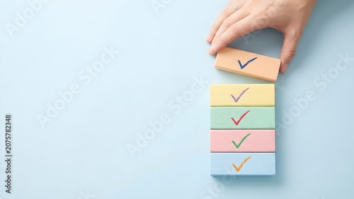 A hand is placing the last colorful block with a checkmark onto a stack of blocks, signifying completion of a task or goal