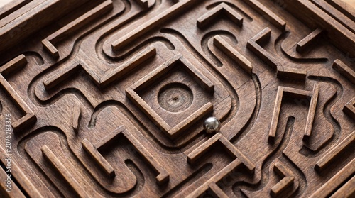 A classic wooden labyrinth with a silver ball resting in the center. The intricate design of the maze challenges the mind and offers a sense of accomplishment upon completion