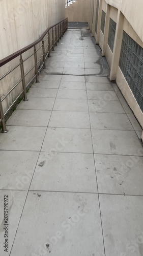 Walking along a sunlit sidewalk beside a building