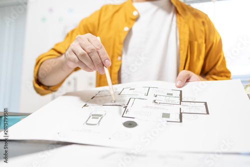 The person is working on architectural design plans, calculating various data. Their focused expression shows meticulous attention to detail, ideal for construction, design, or renovation projects.