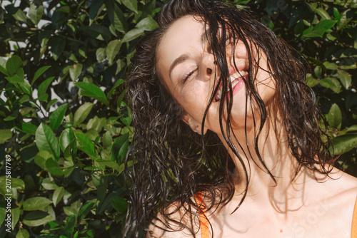 Obraz na plátně Vibrant outdoor portrait of a woman with wet hair, eyes closed, basking in sunli