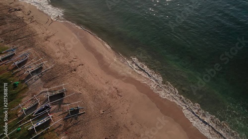 Aerial View of Sandy Beach with Traditional Outrigger Boats, People and Gentle Ocean Waves