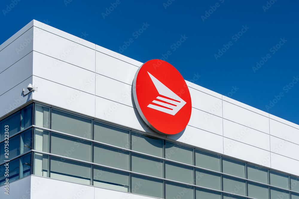 Obraz premium Toronto, Canada - June 27, 2026: Closeup red circular logo of Canada Post displayed on the exterior of a Canada Post facility in Toronto, Canada. Canada Post operates as a federal Crown corporation. 