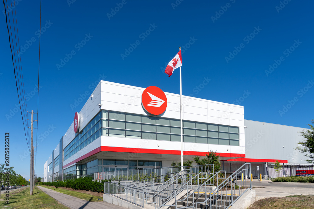 Obraz premium Toronto, Canada - June 27, 2026: Flag of Canada and Canada Post logo displayed on the building in Toronto. Canada Post operates as a federal Crown corporation. 