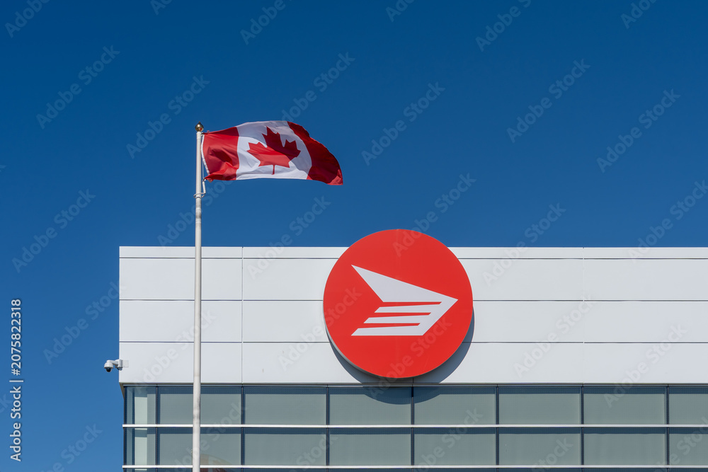 Obraz premium Toronto, Canada - June 27, 2026: Flag of Canada and Canada Post logo displayed on the building in Toronto. Canada Post operates as a federal Crown corporation. 