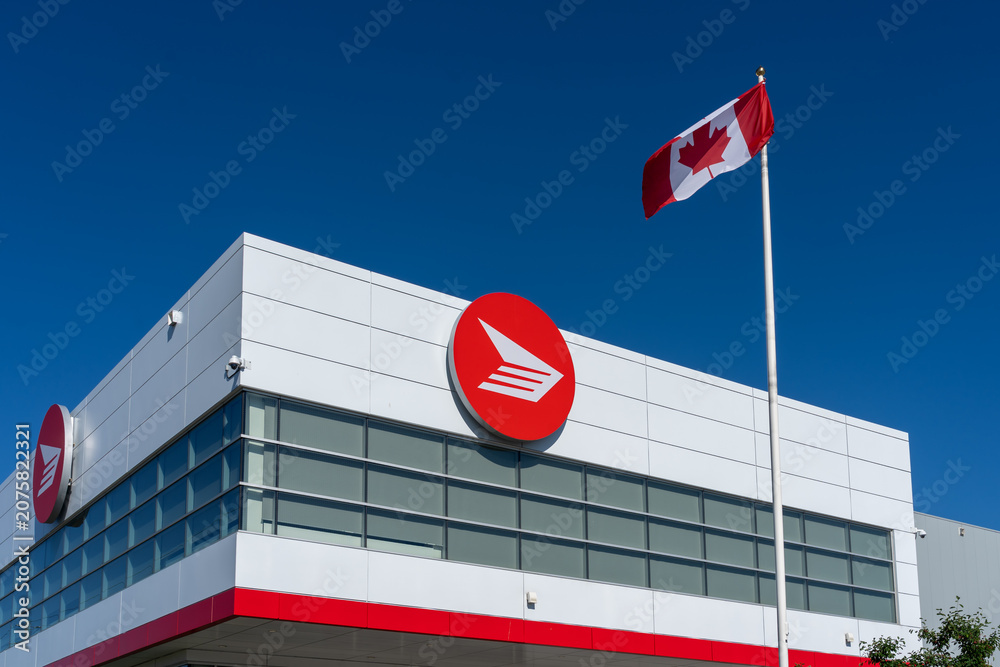 Obraz premium Toronto, Canada - June 27, 2026: Flag of Canada and Canada Post logo displayed on the building in Toronto. Canada Post operates as a federal Crown corporation.