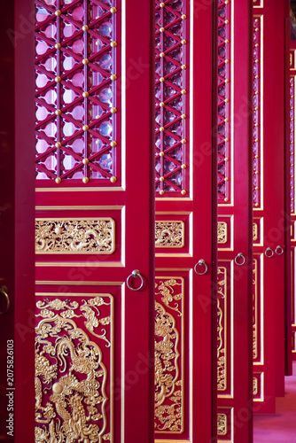 Bild auf Leinwand Intricate red and gold doors with dragon motifs in a traditional Asian temple