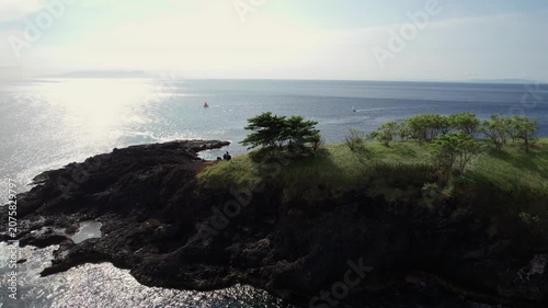 Aerial View of Pulau Paus Rocky Island with Green Grass, Trees and Sunlit Ocean in Bali