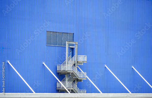 Modern industrial building exterior with blue corrugated metal siding and metal staircase