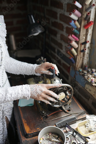 Artisan tailoring delicate white lace fabric using a vintage mechanical sewing machine in a rustic studio