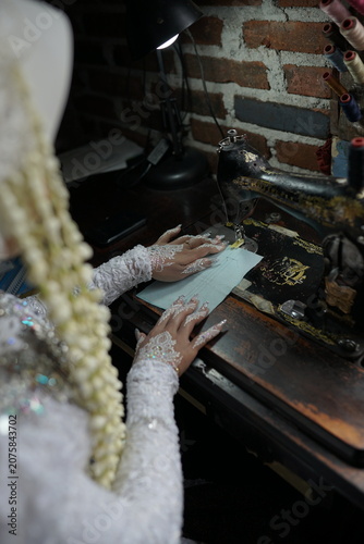 A skilled seamstress focuses on intricate bridal garment construction in a vintage workshop setting