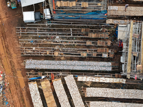 Aerial view of fish drying on wooden racks at the Kali Baru fishing port, with rows of salted fish laid out under the sun in Cilincing, Jakarta, Indonesia.