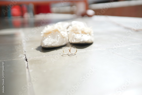 Beautiful Wedding Accessories with White Fluffy Bridal Slippers and Gold Wedding Rings Concept 