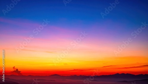 A vibrant sunset paints the sky with fiery hues of orange, red, and purple over silhouetted mountains.