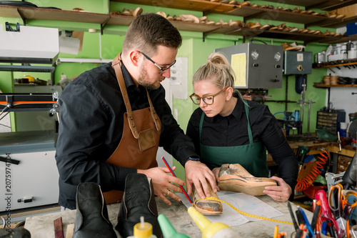 Shoemakers collaborating in workshop designing custom footwear