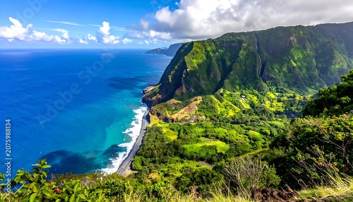 A lush, green cliffside meets a vast, blue ocean under a cloudy sky