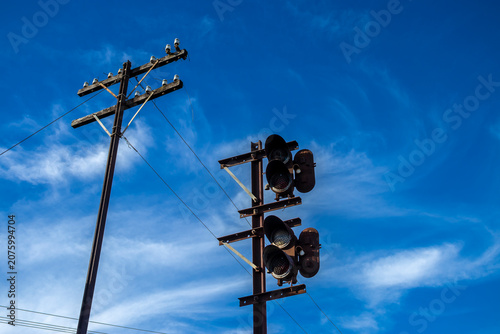 Vintage railway signal and wooden telegraph pole with ceramic insulators stands under a bright blue sky with light clouds in Brazil. 