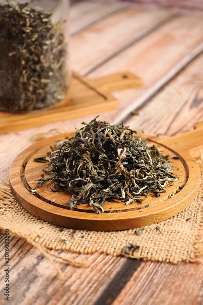 Naklejka premium Dry tea leaves arranged on a wooden board in a kitchen