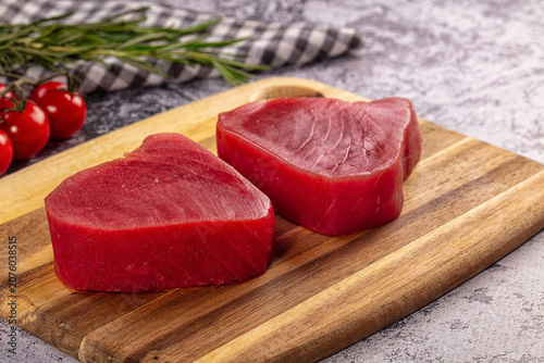 Obraz na płótnie Fresh tuna steaks on wooden cutting board with cherry tomatoes and rosemary