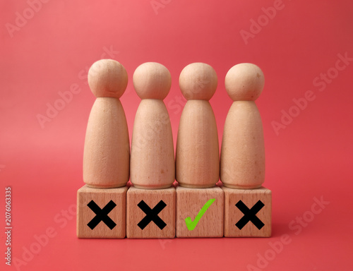 Four wooden peg figures stand on blocks marked with three black cross marks and one green checkmark on red