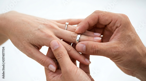 Capturing a close-up moment as a groom delicately places a sparkling wedding ring on his bride's finger, signifying eternal love and the sacred vow of marriage