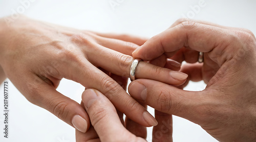 Romantic close-up of a man putting a gold wedding ring on a woman's finger, symbolizing love and marriage commitment