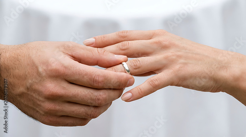 Close-up of a groom placing a wedding band on a bride's finger during a marriage ceremony, representing love and union