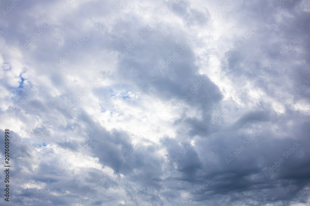 Fototapeta premium Blue Sky with Thick Layered Rain Clouds and Dramatic Weather. A textured blue sky partially covered by thick gray rain clouds creating an impressive dramatic weather scene. Perfect natural background 