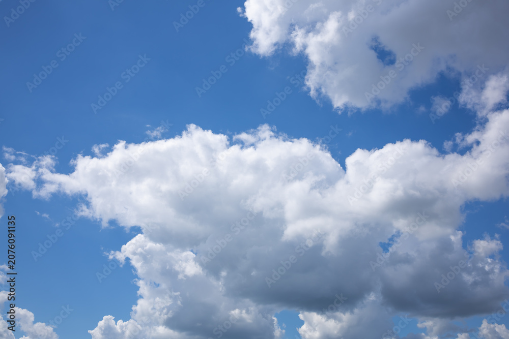 Fototapeta premium Bright daytime sky with textured white clouds. Beautiful dramatic blue sky with large white cumulus clouds before summer rain. Natural cloudscape with dynamic formations