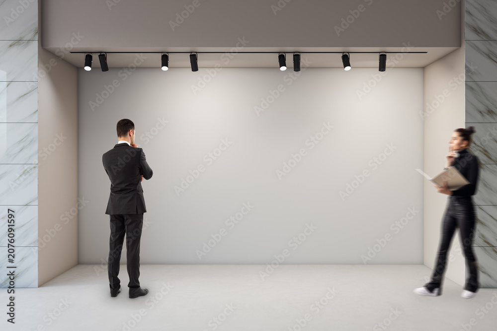 Obraz premium Businesspeople observing an empty gallery wall under spotlights in a modern museum interior room with marble accents and soft lighting concept scene.