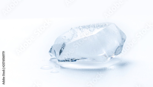 Irregular clear ice chunk with droplets on clean white surface 氷の塊と水滴の白背景素材