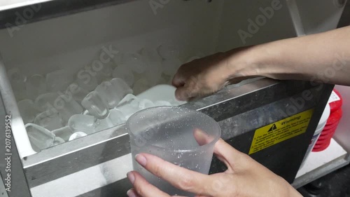 Ice scoop plastic cup filling frozen cubes at food service machine for beverage preparation in commercial kitchen environment