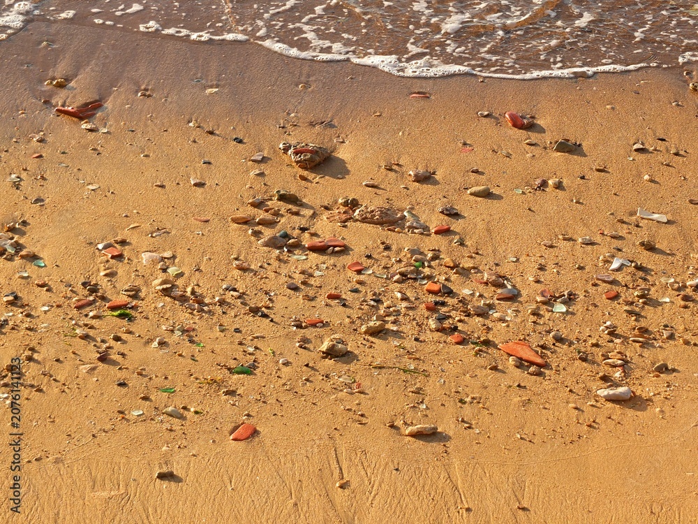 Fototapeta premium Sandy beach with colorful sea glass and pottery shards