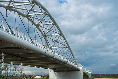 a modern metal bridge inside the Polesine campaigns with a cloudy sky in the background, Rovigo, Italy 