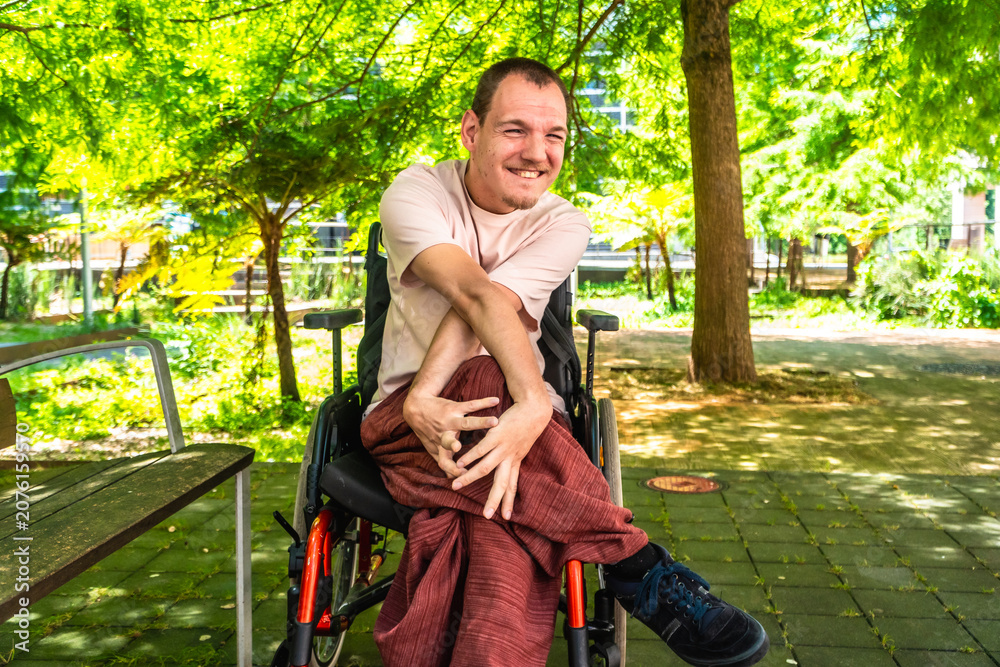 Obraz premium Smiling man with cerebral palsy in wheelchair enjoying park