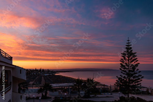 Foto Dramatic pink sunset sky over a calm bay and beach resort